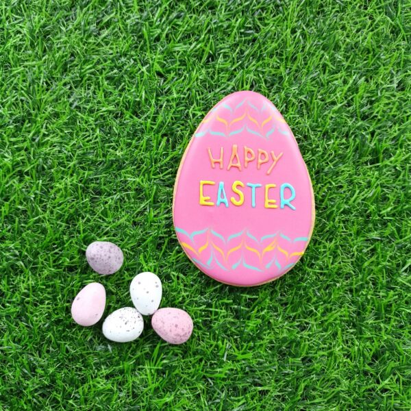 pink Easter Egg biscuit with feathering on green background